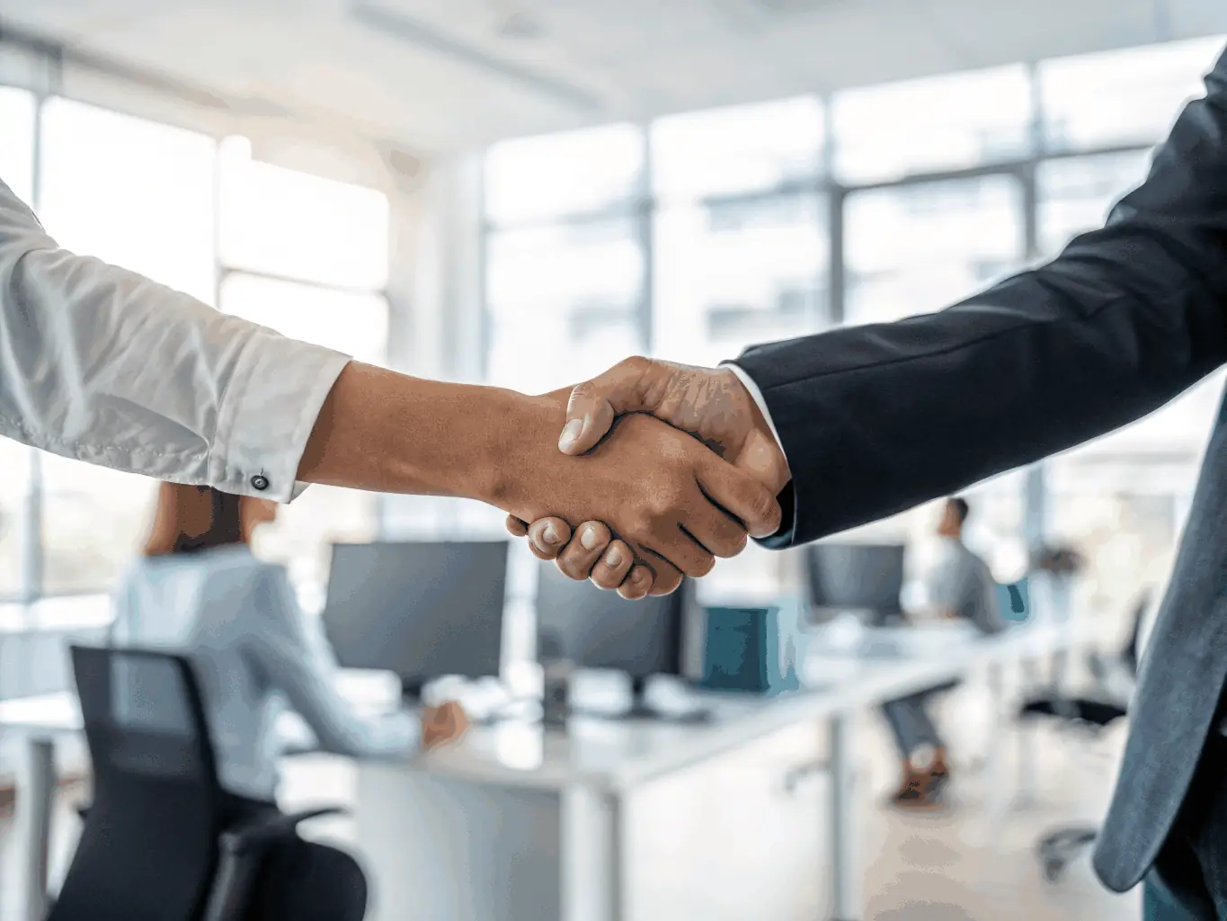 A close-up of a consultant and a startup founder shaking hands across a conference table, with documents and laptops visible, symbolizing partnership, trust, and collaborative success in consulting.